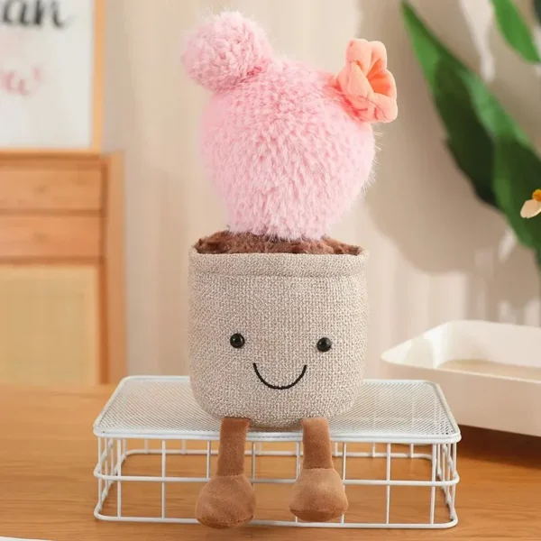 Peluche cactus rose design Jellycat, visage kawaii, pot beige et jambes pendantes.
