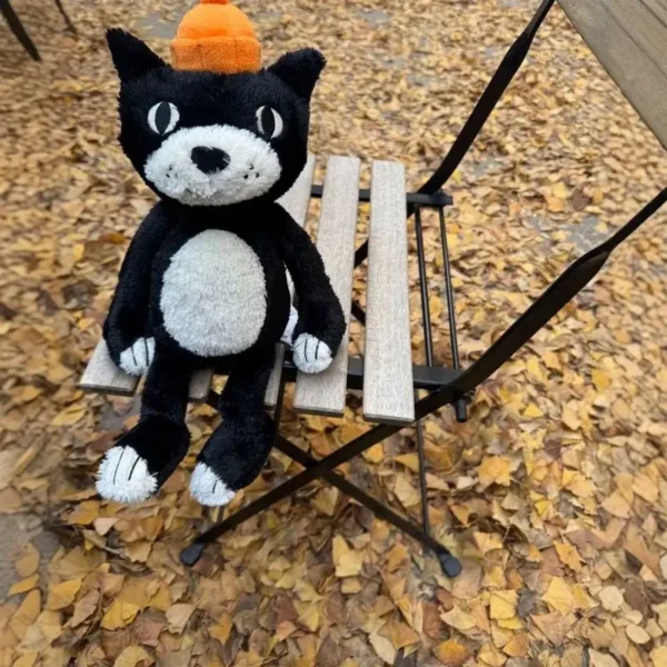 Peluche chat Jelly Vibe noire et blanche 32 cm, bonnet orange vif, douceur premium.