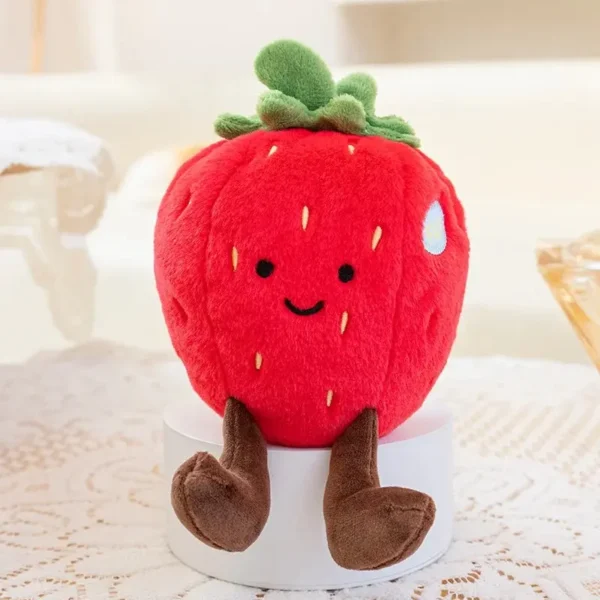 Peluche fraise rouge vif façon Jellycat, design kawaii assise sur un socle blanc.