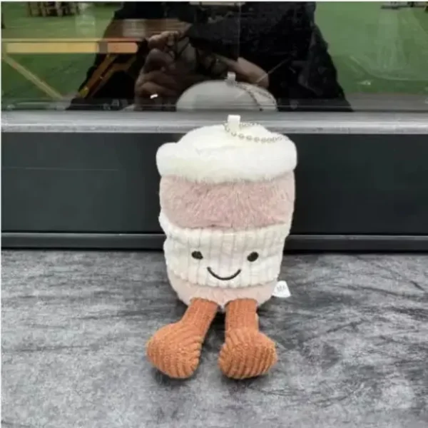 Peluche café rose pâle style Jellycat, mousse blanche, visage kawaii et chaîne.